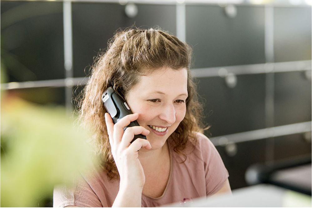 Eine Kollegin telefoniert lächelnd am Empfang